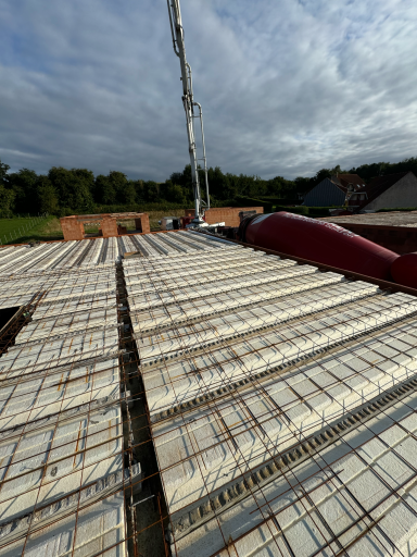 coulage étage Vue d'un toit en construction avec des planches de béton et une grue en arrière-plan.
