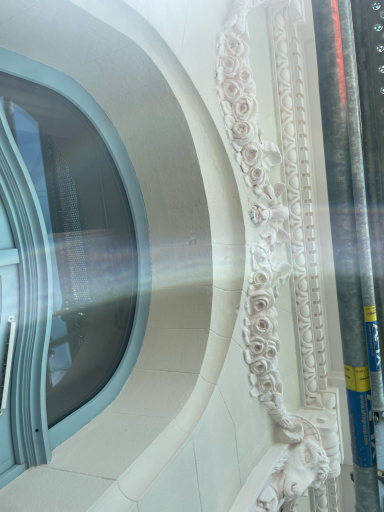 Détail architectural en relief avec fenêtre ornée et lumière glissante.